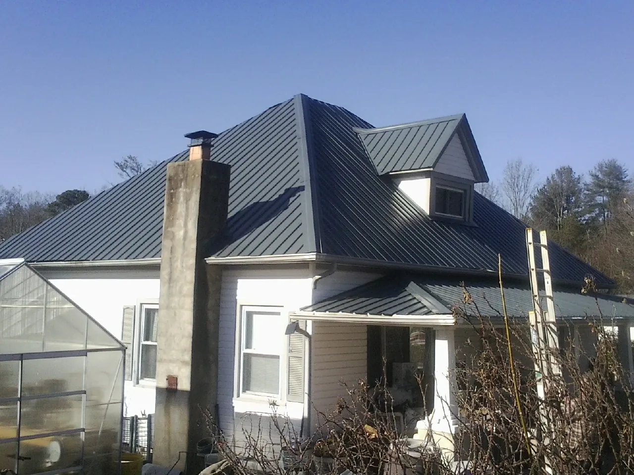 Dark blue standing seam metal roof on a white farmhouse with dormer — Slate & Tile Roof Repair by Roofing Brothers in Chesapeake City
