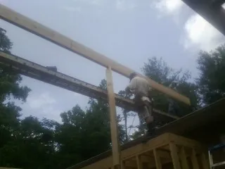 Carpenter setting a ridge beam over a new addition frame — Ice Dam Removal by Roofing Brothers in Chesapeake City