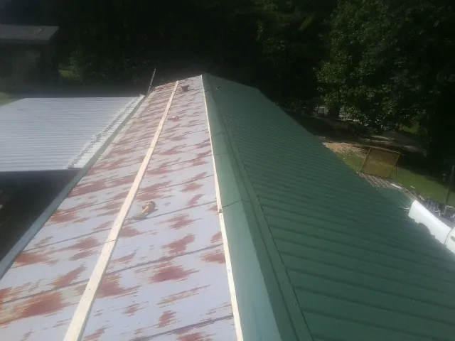 Old rusted panels beside newly installed green metal roofing — Wind Damage Roof Repair by Roofing Brothers in Chesapeake City