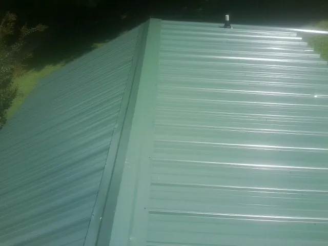New green metal panels meeting at the ridge of a roof — Flat Roof Repair work by our crew in Chesapeake City