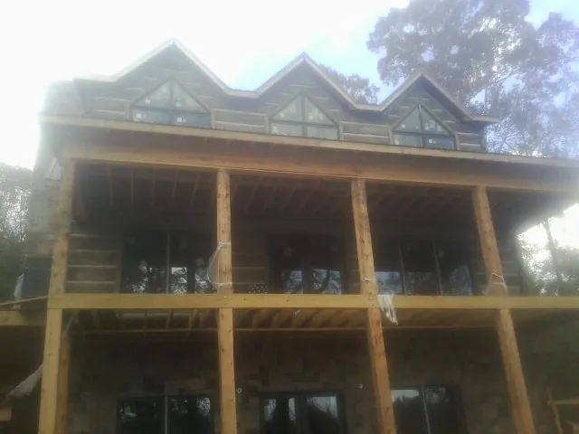 Dormers and porch framing on a large log home under construction — Roof Coating work by our crew in Chesapeake City