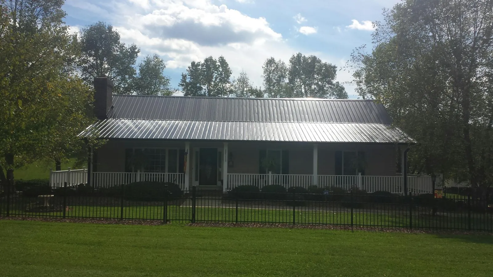 Gray metal roof on a brick ranch with a full width front porch — Gutter Guard Installation work by our crew in Chesapeake City