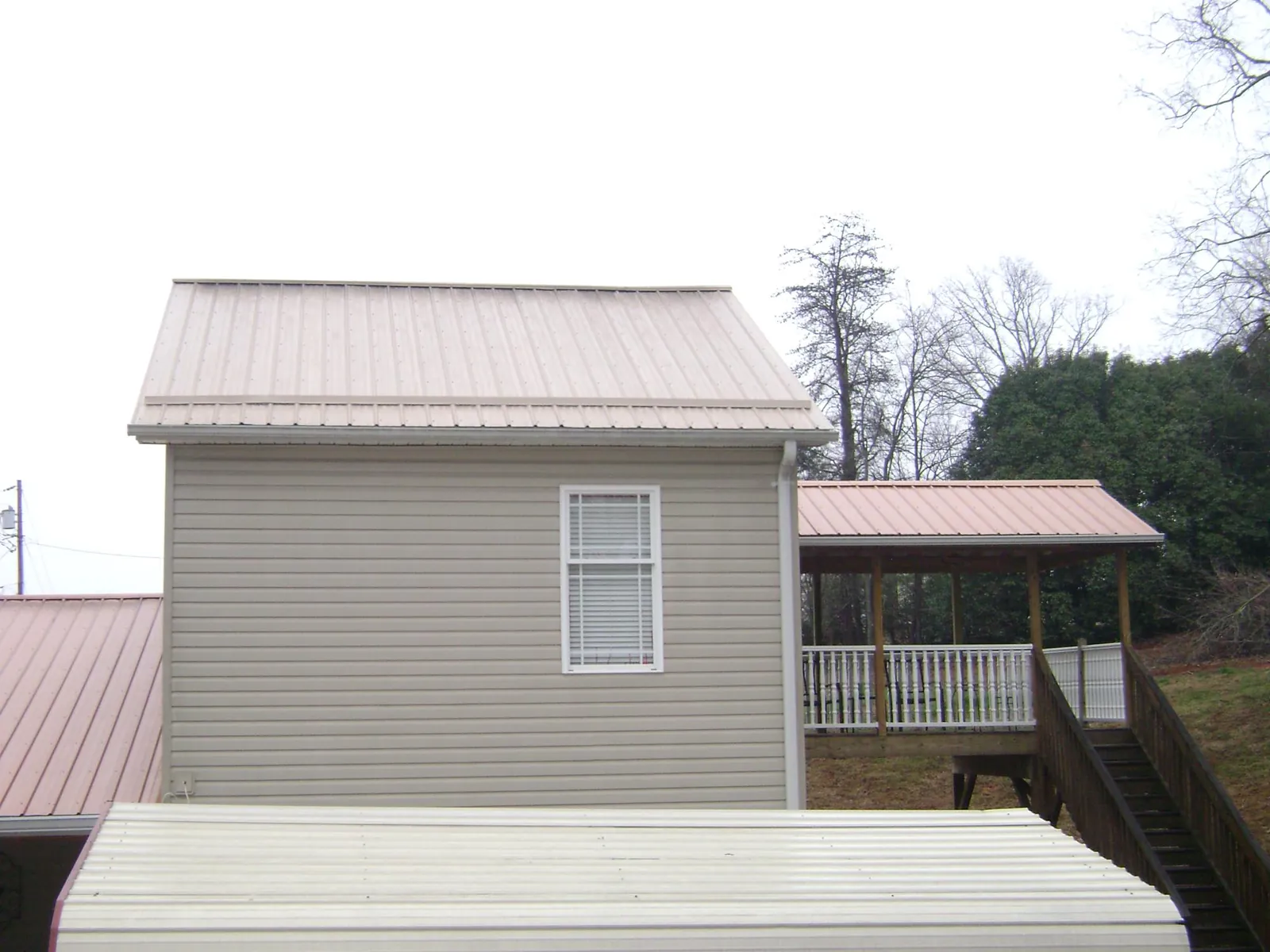 Tan metal roofs on a two story addition and attached porch, from a Roof Replacement job in Chesapeake City