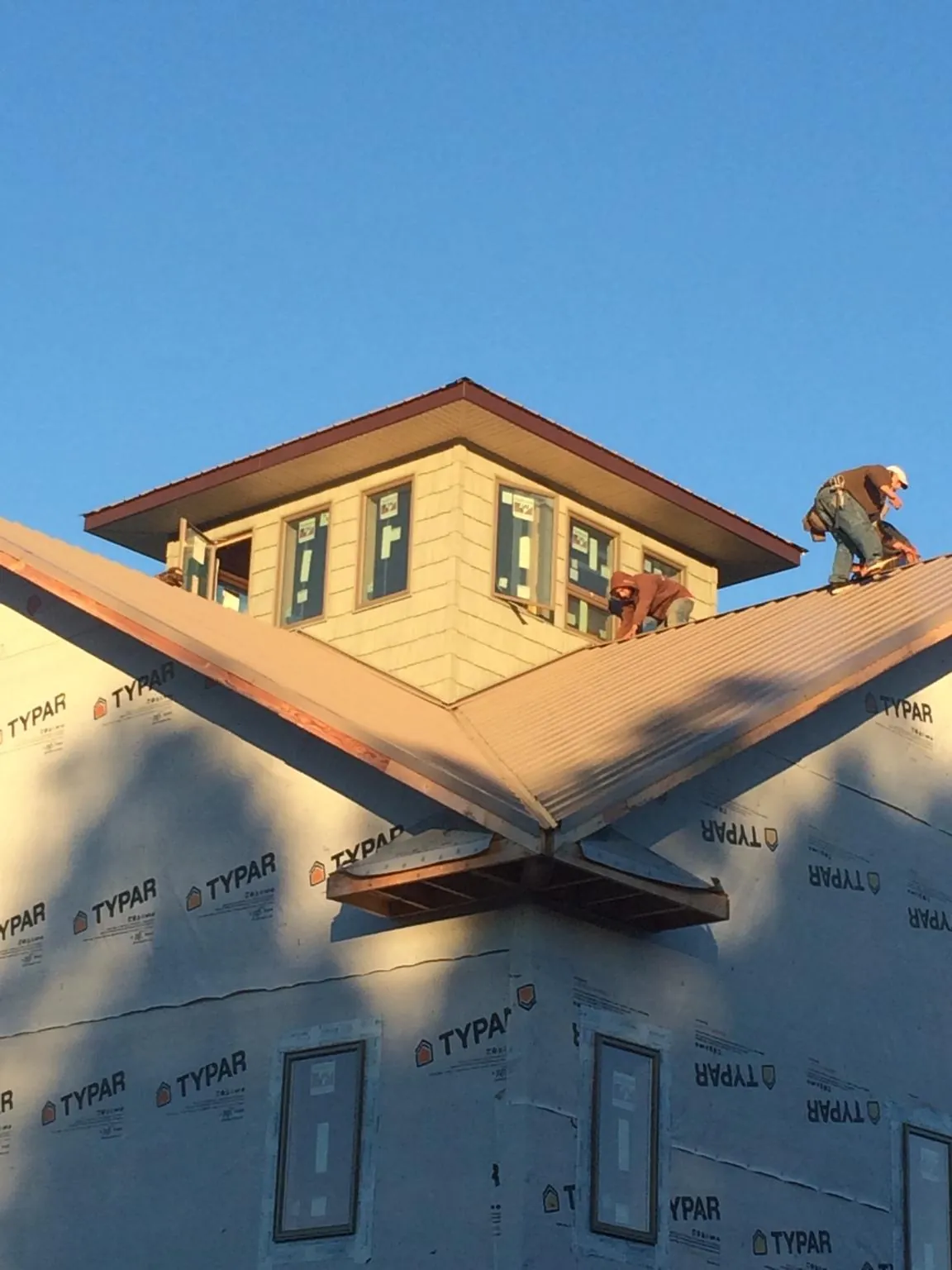 Roofers working around a rooftop cupola on a new metal roof at sunset — Roof Waterproofing in Chesapeake City by Roofing Brothers
